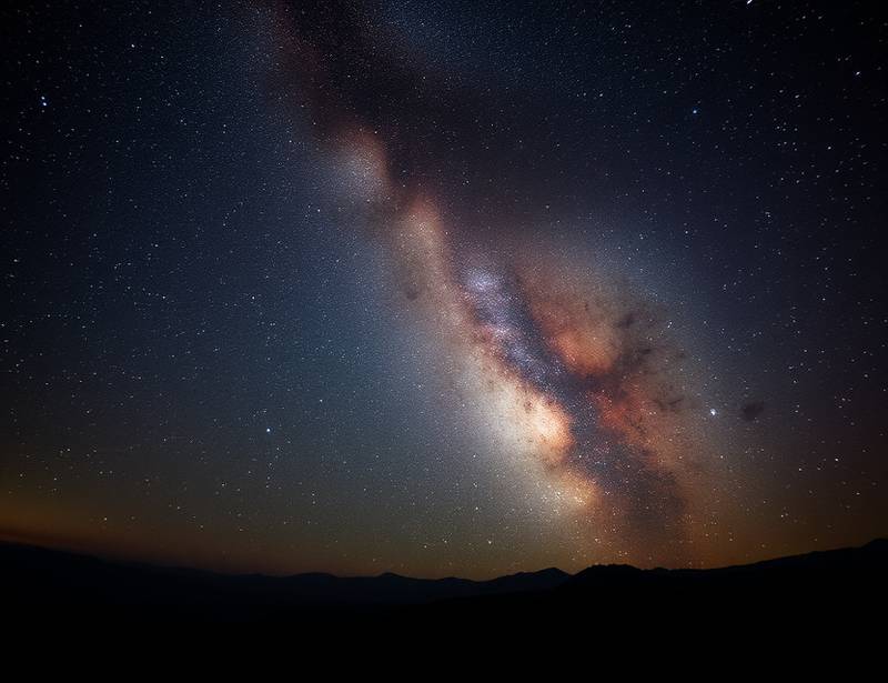 A breathtaking image of the Milky Way over a dark landscape, representing night photography.